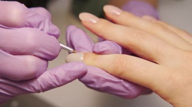 Close up video of nail master applying gel on nails at salon.