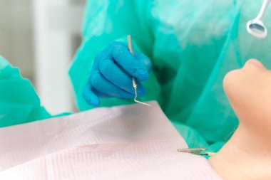 Close up shot of a dentist hand wearing blue glove and holding profesional tool.