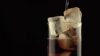 Close up footage of pouring cola in glass with ice.