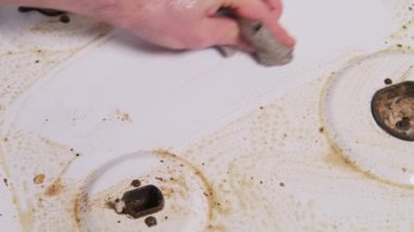 Close up video of man hand washing and cleaning gas stove.