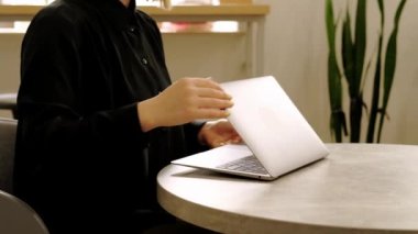 Footage of woman closing laptop and going home from cafe meeting.