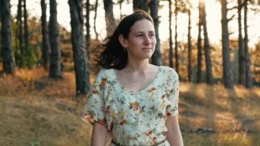 Video of happy young woman walking in pine forest during sunset and relaxing.