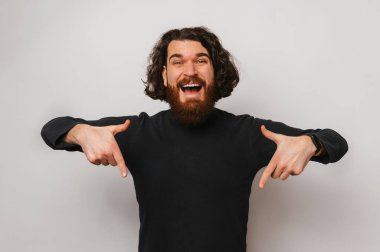 Look at this offer right here says a man while pointing down with both hands. Studio shot over gray background.