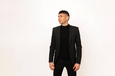 Studio portrait over white background of a young standing man wearing a black jacket.