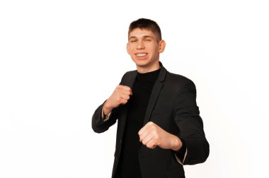 Wide smiling young man wearing jacket is standing in the pose ready to defence himself.