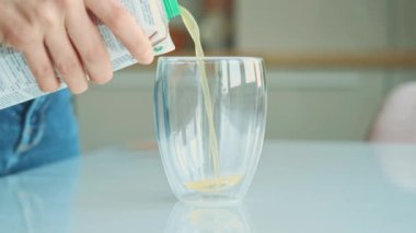 Close up video of woman pouring orange juice in a glass at kitchen.