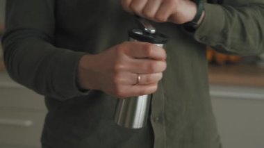 Mutfaktaki kahve çekirdeklerini öğütücü ile öğüten adamın videosunu kapat..