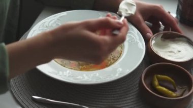 Close up video of woman sitting in kitchen and eating Russian Chicken Soup.