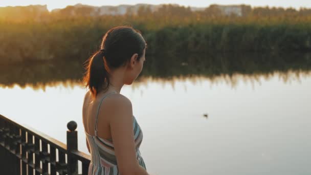 Відео Молодої Жінки Стоїть Біля Міського Озера Парку Насолоджується Заходом — стокове відео