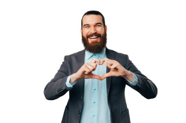 Ceket giyen yakışıklı, sakallı adam göğsüne kalp hareketi yapıyor..