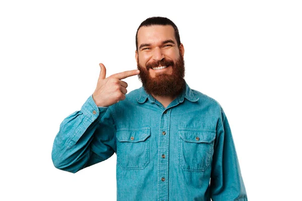 Wesoły Brodaty Hipster Niebieskiej Koszuli Wskazuje Swój Piękny Uśmiech — Zdjęcie stockowe