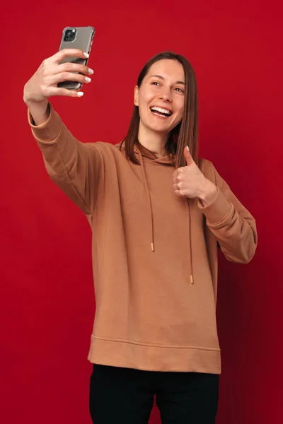 Vidám Fiatal Csinál Egy Szelfit Telefonjával Miközben Mutatja Hüvelykujját Piros — Stock Fotó