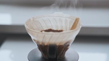 Kahvenin üzerine dökülen demlenme videosunu kapatın. Mutfakta taze kavrulmuş kahve çekirdekleri ve güzel bir buharla..