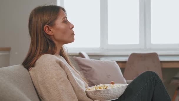 Nagranie Młodej Kobiety Siedzącej Kanapie Jedzącej Popcorn Szukającej Filmu Obejrzenia — Wideo stockowe