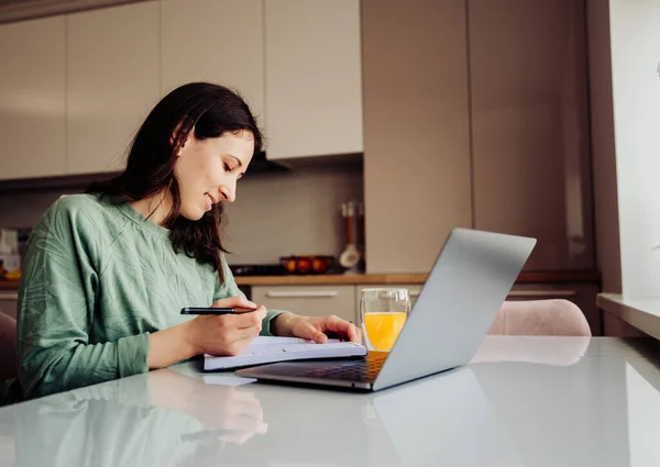 Χαρούμενη Γυναίκα Γράφει Στο Ημερολόγιό Της Ενώ Κάθεται Laptop Στην — Φωτογραφία Αρχείου