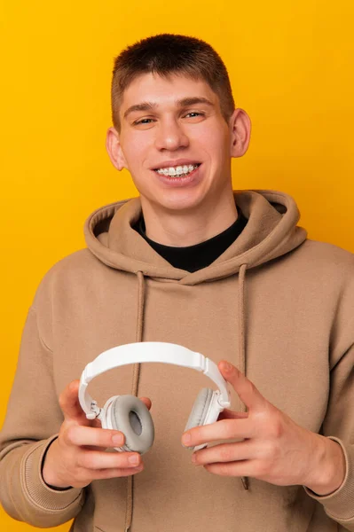 Retrato Vertical Hombre Sonriente Con Capucha Sosteniendo Auriculares Blancos Sobre —  Fotos de Stock