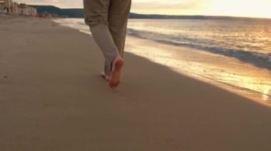Gün doğarken sahilde yürüyen kadının düşük açılı görüntüleri..