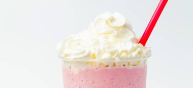 Banner yakın plan çilekli milkshake 'in üstüne krema ve kırmızı bir pipet..