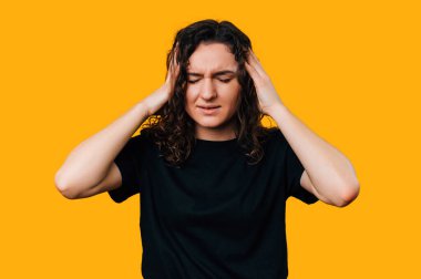 Genç esmer kadın kafasına dokunuyor zor bir gün ve kötü bir baş ağrısı var. Sarı arkaplan üzerinde stüdyo resmi.