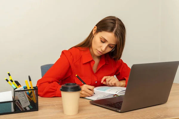 Konzentrierte Frau Schreibt Ihren Planer Während Sie Mit Geöffnetem Laptop — Stockfoto