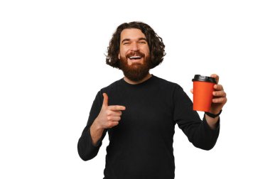 Yakışıklı sakallı adam beyaz arka planda tuttuğu kırmızı bardağı işaret ediyor..