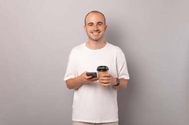 Yakışıklı genç kel adam internette geziniyor ve kahvenin tadını çıkarıyor..