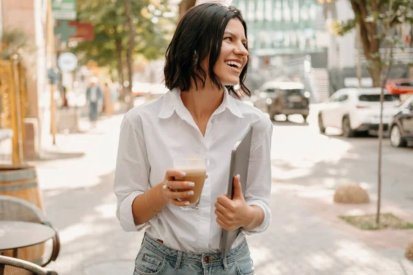 Jovem Mulher Sorridente Andando Livre Enquanto Segura Laptop Copo Latte — Fotografia de Stock