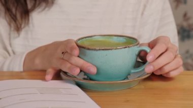 Kadının elinde bir fincan matcha latte ile ısınma videosunu kapat..
