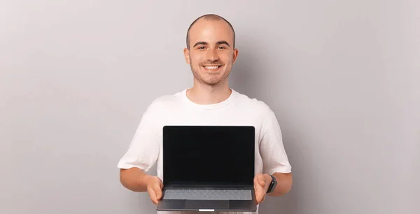 Dazlak Bir Adamın Elinde Dizüstü Bilgisayarla Gri Arka Planda Kameraya — Stok fotoğraf