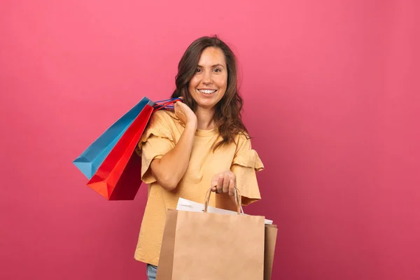 Fröhlich Lächelnde Junge Frau Hält Ein Paar Einkaufstüten Über Rosa — Stockfoto