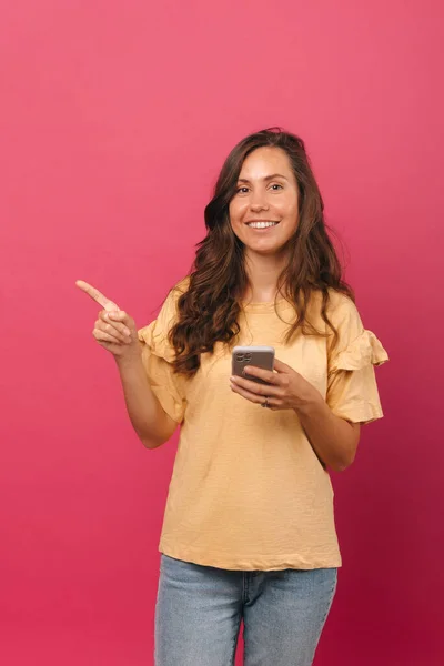 Vertical Shot Young Woman Pointing Aside While Holding Her Phone — Stock Photo, Image