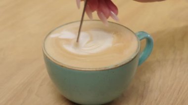 Kapuçino köpüğü karıştıran kadının videosunu kapat.