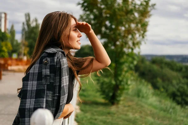 stock image Romantic young woman is looking far while making shadow with her hand above eyes.