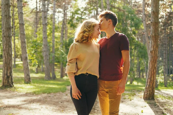 男は彼の女性にキスをしている間森の中で日光の下で平和なカップルは お互いの存在をお楽しみください — ストック写真