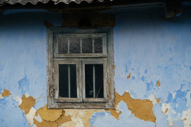 Maviyle boyanmış eski terk edilmiş bir evde küçük bir pencerenin yakın çekim görüntüsü..