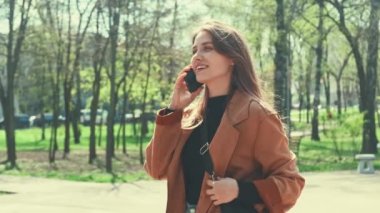 Beyaz tenli güzel bir kadının açık havada akıllı telefondan konuştuğu bir video..