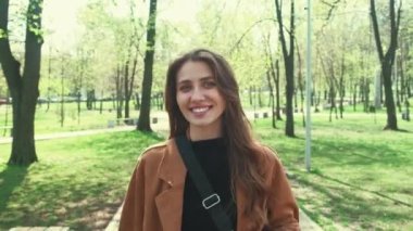 Genç ve çekici bir kadının bahar zamanı şehir parkında yürüyüş videosu..