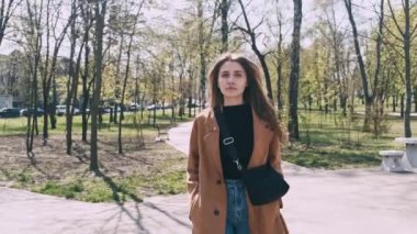 Genç moda kadınının bahar günü şehir parkında yürüyüş videosu..