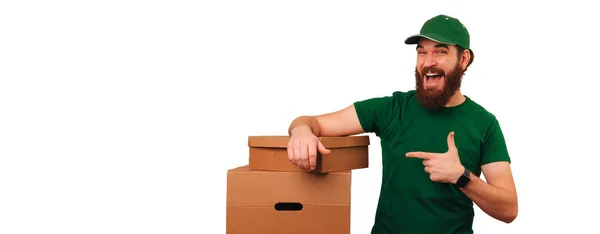 Playful Young Bearded Delivery Man Pointing Boxes Leaning Banner Shot — Stock Photo, Image