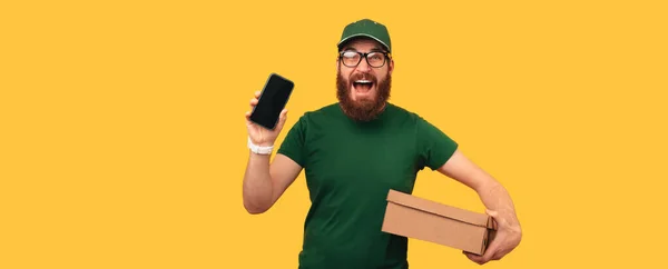 一个男人的横幅照片拿着一个他要送的盒子 把他的手机屏幕显示在耶鲁的背景下 — 图库照片