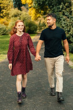 Birbirine aşık genç bir çiftin parkta yürürken dikey çekimi..