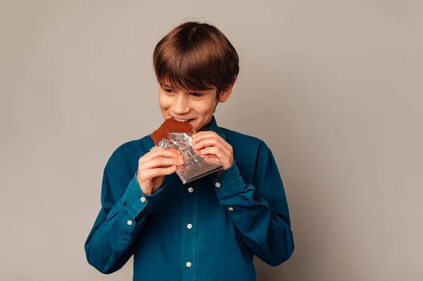 Boldog Fiatal Fiú Kék Inget Visel Élvezi Csokit Miközben Harapdálja — Stock Fotó