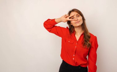 Yakışıklı, gülümseyen sarışın kadın, jestini gözünün üstünde tutuyor.