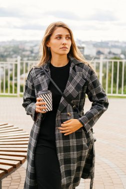 Elinde kahve fincanı olan yakışıklı bir kadının dikey portresi..