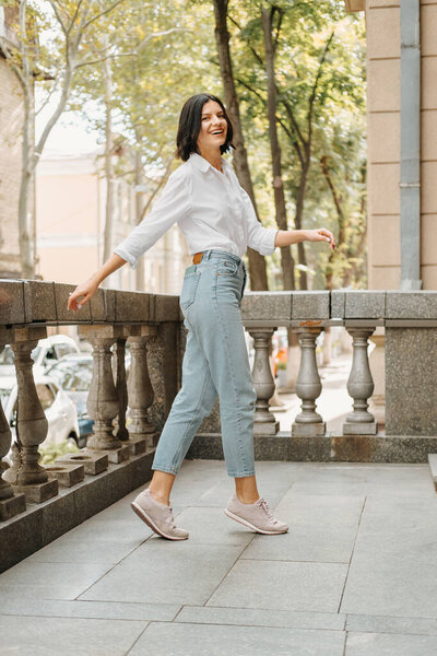 Полный снимок портрета молодой расслабленной женщины танцует на улице в солнечный день.