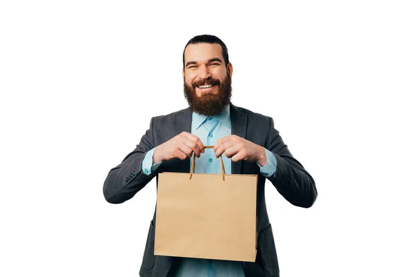 stock image Cheerful handsome bearded man wearing a jacket is holding a shopping bag with copy space.