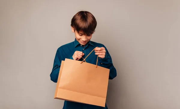 如果有什么他喜欢的东西 好奇的少年正在查看他拿着的购物袋 — 图库照片