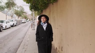 Barcelona 'da sokakta yürüyen genç bir kadının yavaş çekim görüntüleri. Siyah ceketli ve şapkalı bir kadının 4K 'lık görüntüsü..
