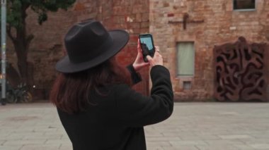 Barcelona 'da güzel bir tuğla binanın fotoğrafını çeken bir kadının yavaş çekim görüntüleri. Yüksek kalite 4k görüntü.
