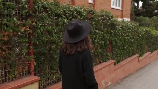黒いコートと帽子を被った若い女性の顔のない映像が通りを歩いている 高品質4K映像 — ストック動画